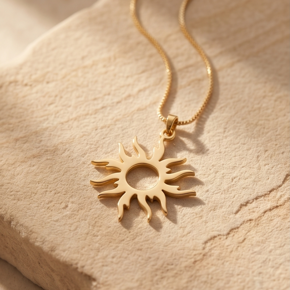 Gold sun-shaped pendant necklace on a beige stone surface