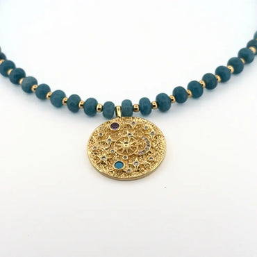 Necklace with blue beads and a gold decorative pendant on a white background