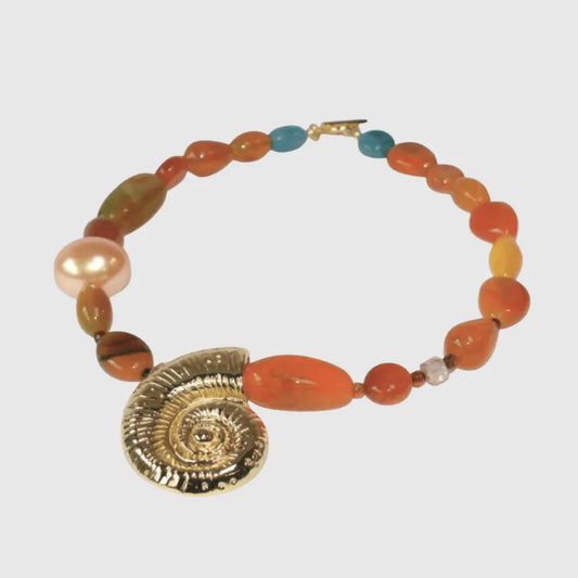 Necklace with natural agate beads in warm tones and gold spiral shell pendant worn on model