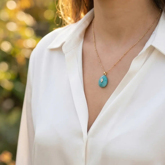 Woman wearing delicate gold necklace with amazonite pendant in natural light