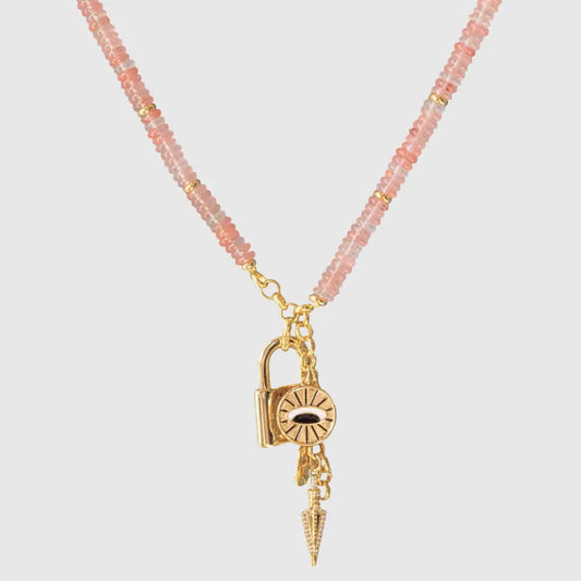 Pink gemstone beaded necklace with gold spiritual charms including padlock, evil eye and pointed talisman on light background