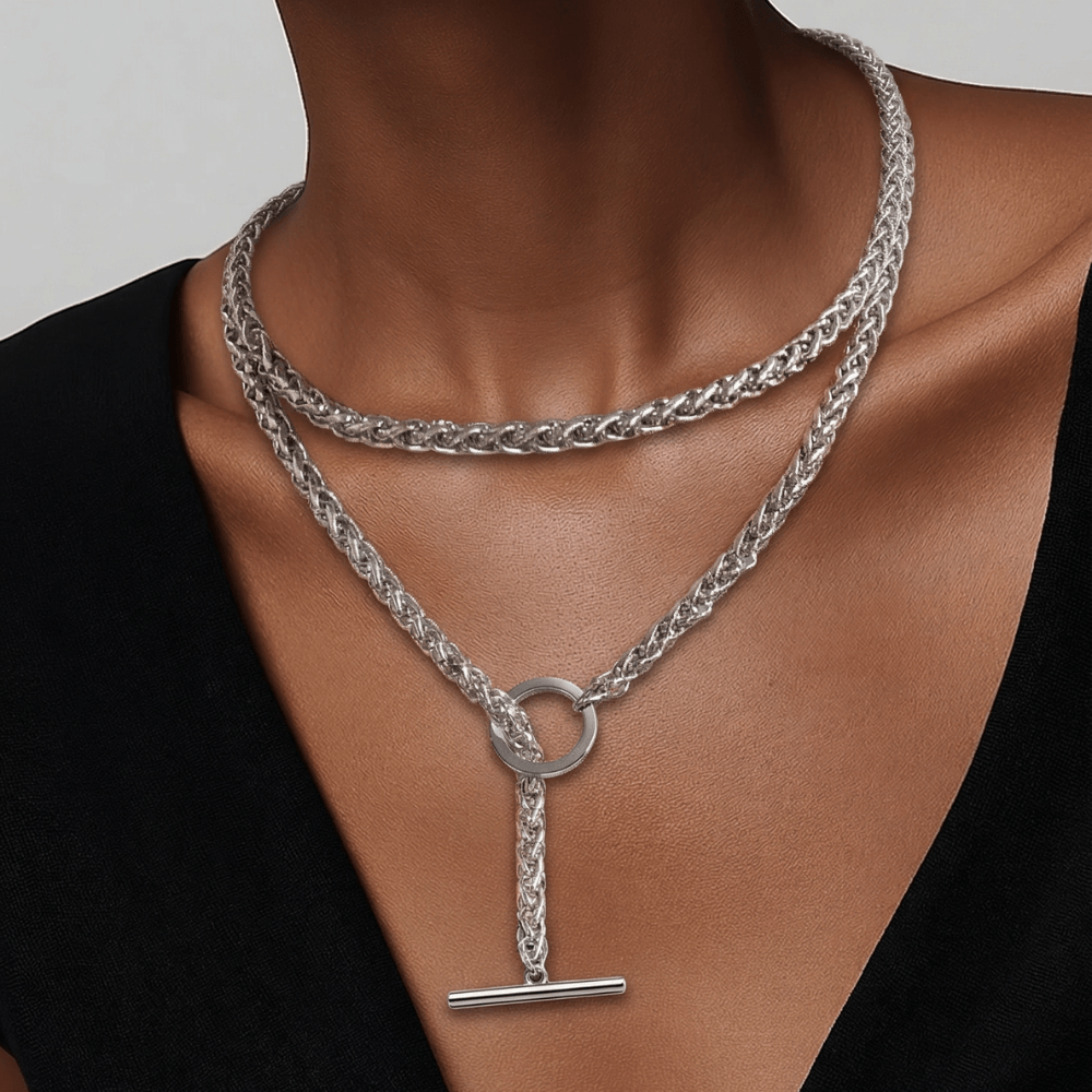 Silver chain necklace with a pendant on a person wearing a black top against a neutral background