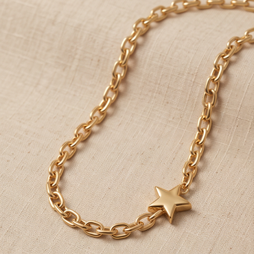 A gold chain necklace with a small star charm, displayed on a textured beige linen fabric background.