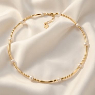 Gold necklace with pearls on a soft beige fabric background