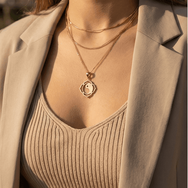 woman wearing gold yin yang lotus necklace minimalist spiritual jewelry outdoor sunlight