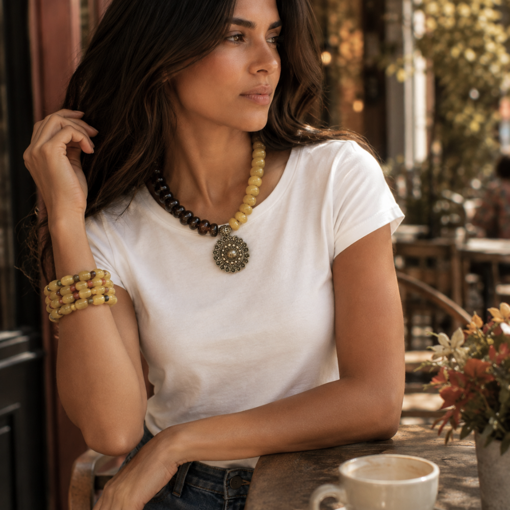Woman wearing Golden Earth brown and mustard statement necklace with antique gold medallion in a fall lifestyle setting