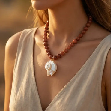Woman wearing Golden Shell 18 inch necklace with shimmering Goldstone beads and mother-of-pearl shell pendant