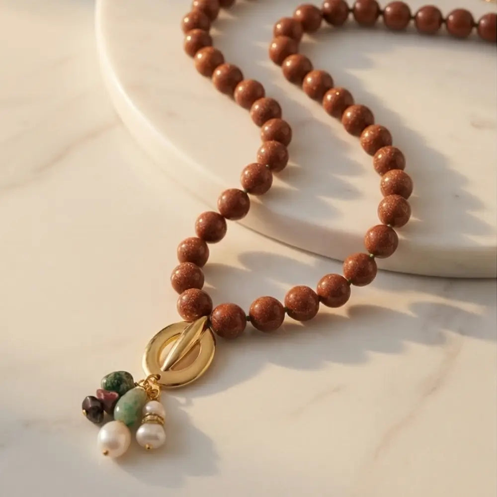 Goldstone necklace with gold pendant and pearl charms flat lay handmade design