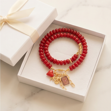 Red beaded bracelet with gold charms in a white box