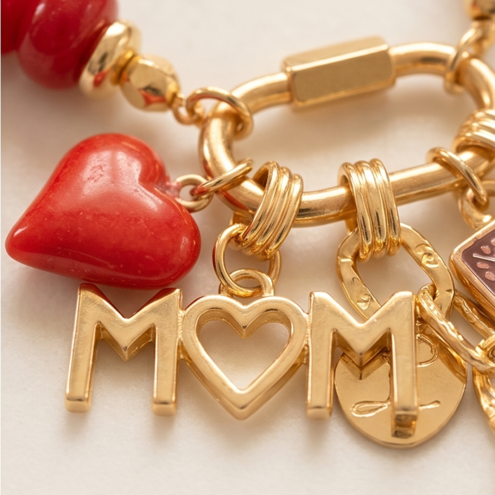 Gold bracelet with 'MOM' charm and red heart on a light background