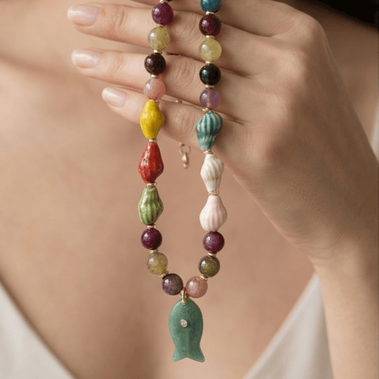 Colorful beaded necklace with fish pendant held in hand unique handmade jewelry