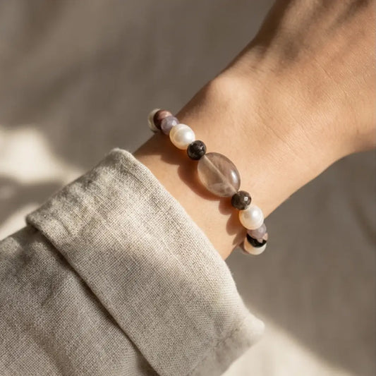 Woman wearing neutral pearl and gemstone bracelet with smoky quartz