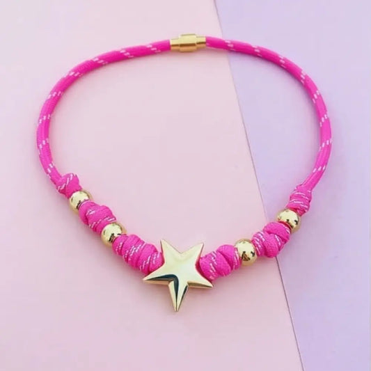 Pink necklace with gold accents and a star pendant on a pink background