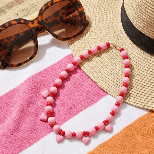 pink red beaded necklace flat lay with sunglasses and hat summer styling