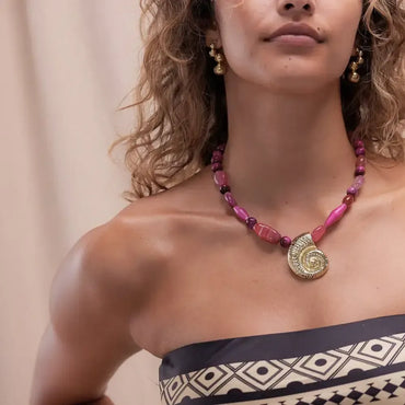 "Handcrafted necklace with vibrant fuchsia gemstone beads and gold spiral shell pendant – coastal statement jewelry for women"
