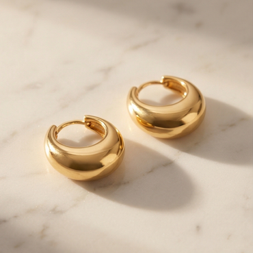 Gold hoop earrings on a marble surface