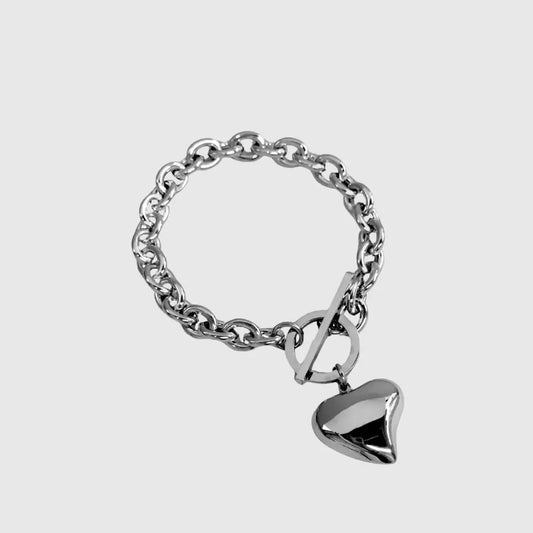 Silver chain bracelet with a heart-shaped tag on a light gray background