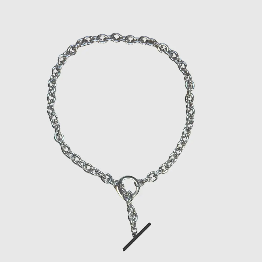 Silver chain bracelet with a small black clasp on a light gray background