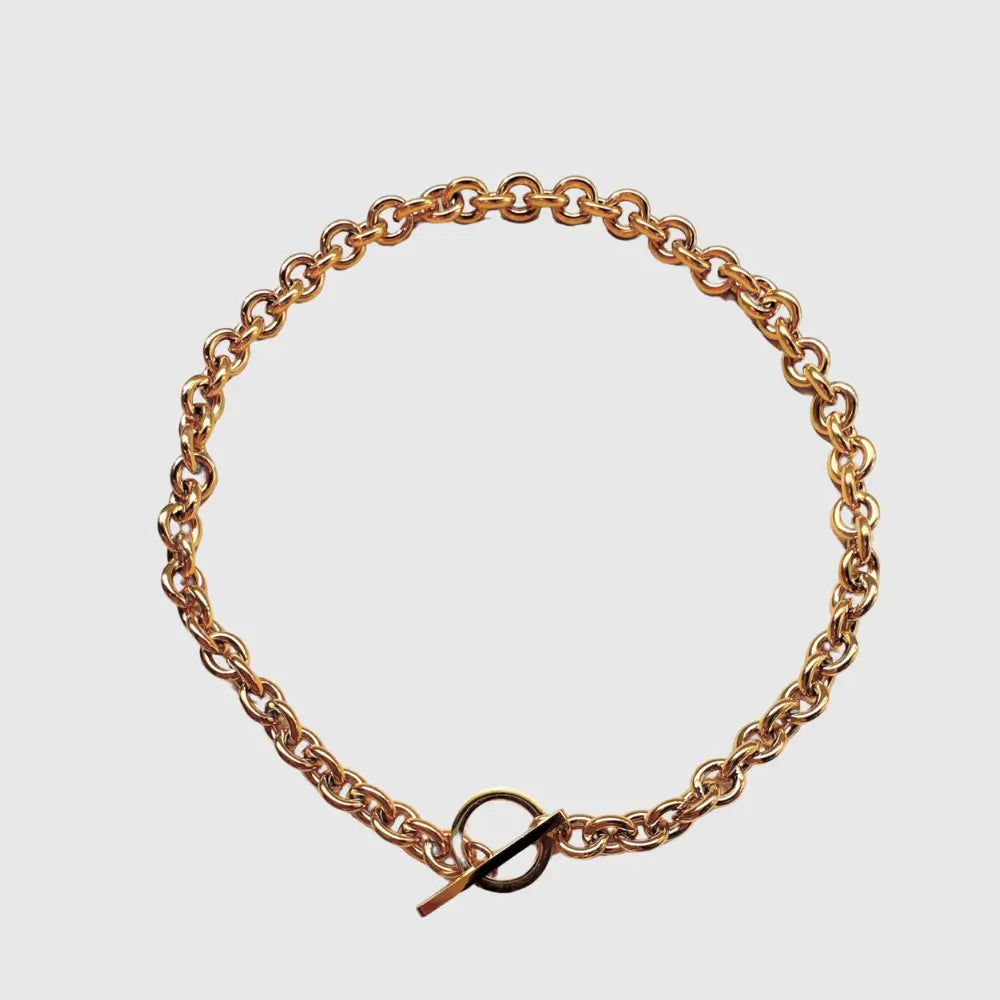 Gold chain bracelet on a light gray background