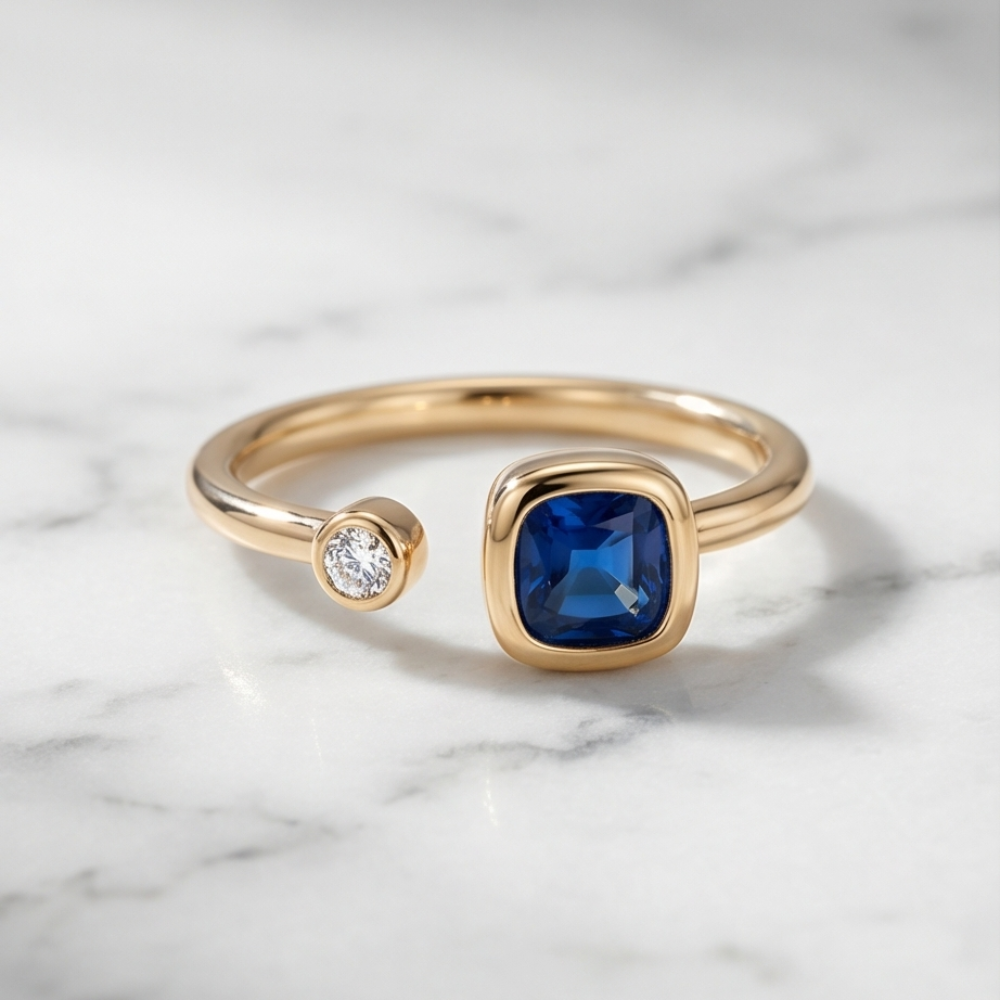 Gold ring with a blue gemstone and smaller diamond on a marble background