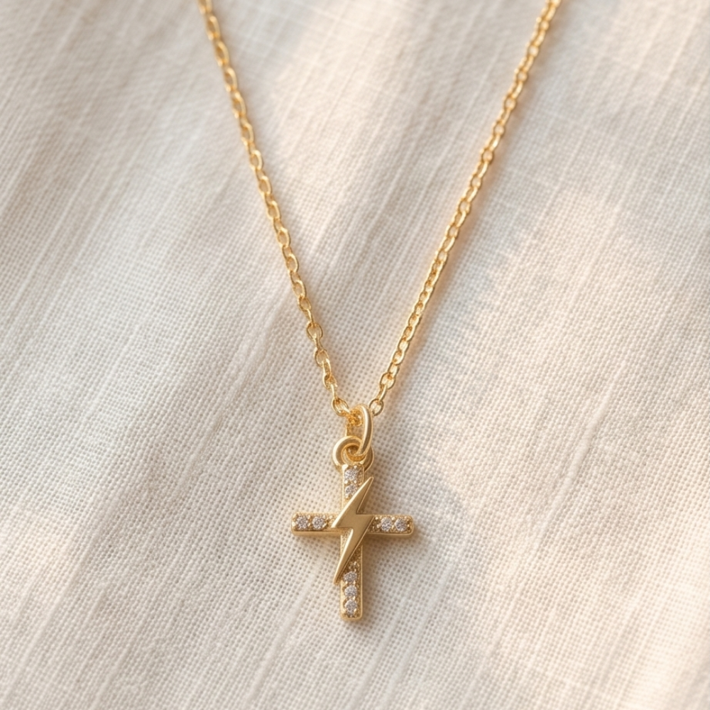 Gold necklace with a cross pendant on a light fabric background