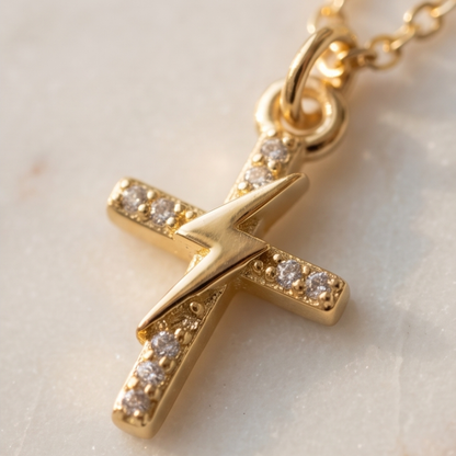 Gold cross pendant with embedded diamonds on a light background