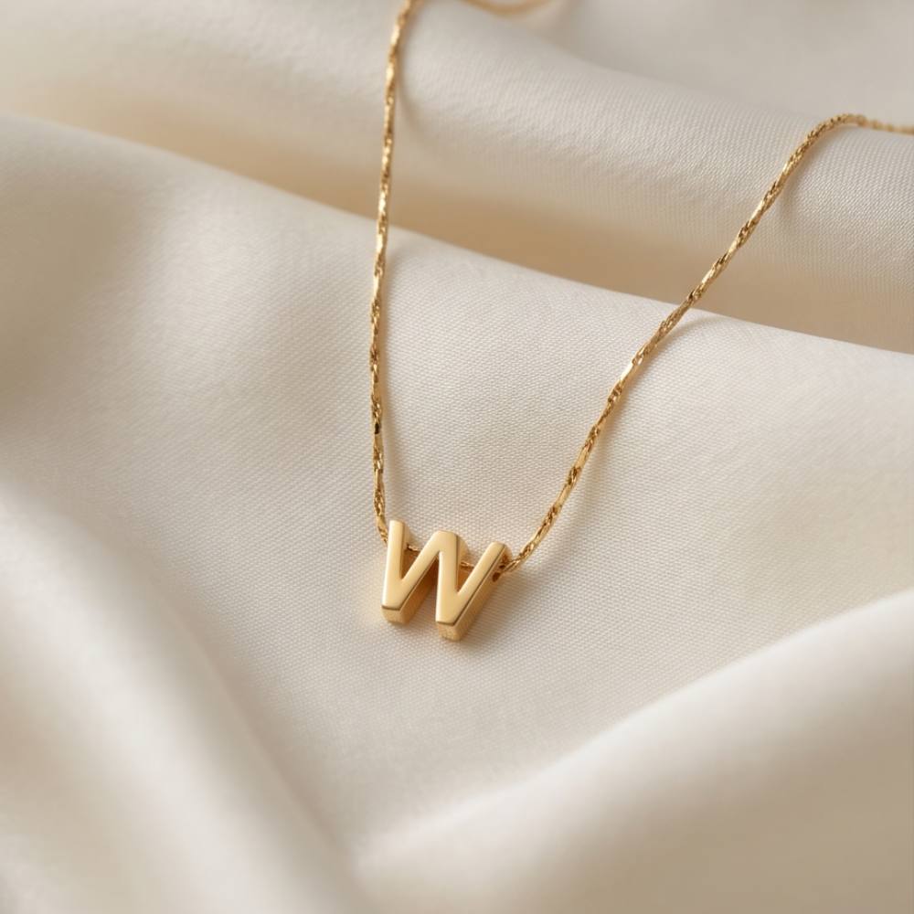 8K gold plated double initial necklace displayed on soft satin fabric