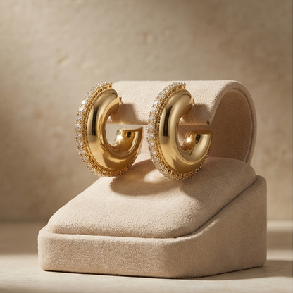 Gold earrings on a beige stand with a neutral background