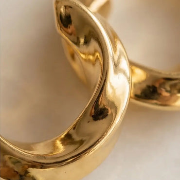 close up of 18k gold plated huggie hoop earrings smooth polished lightweight gold jewelry