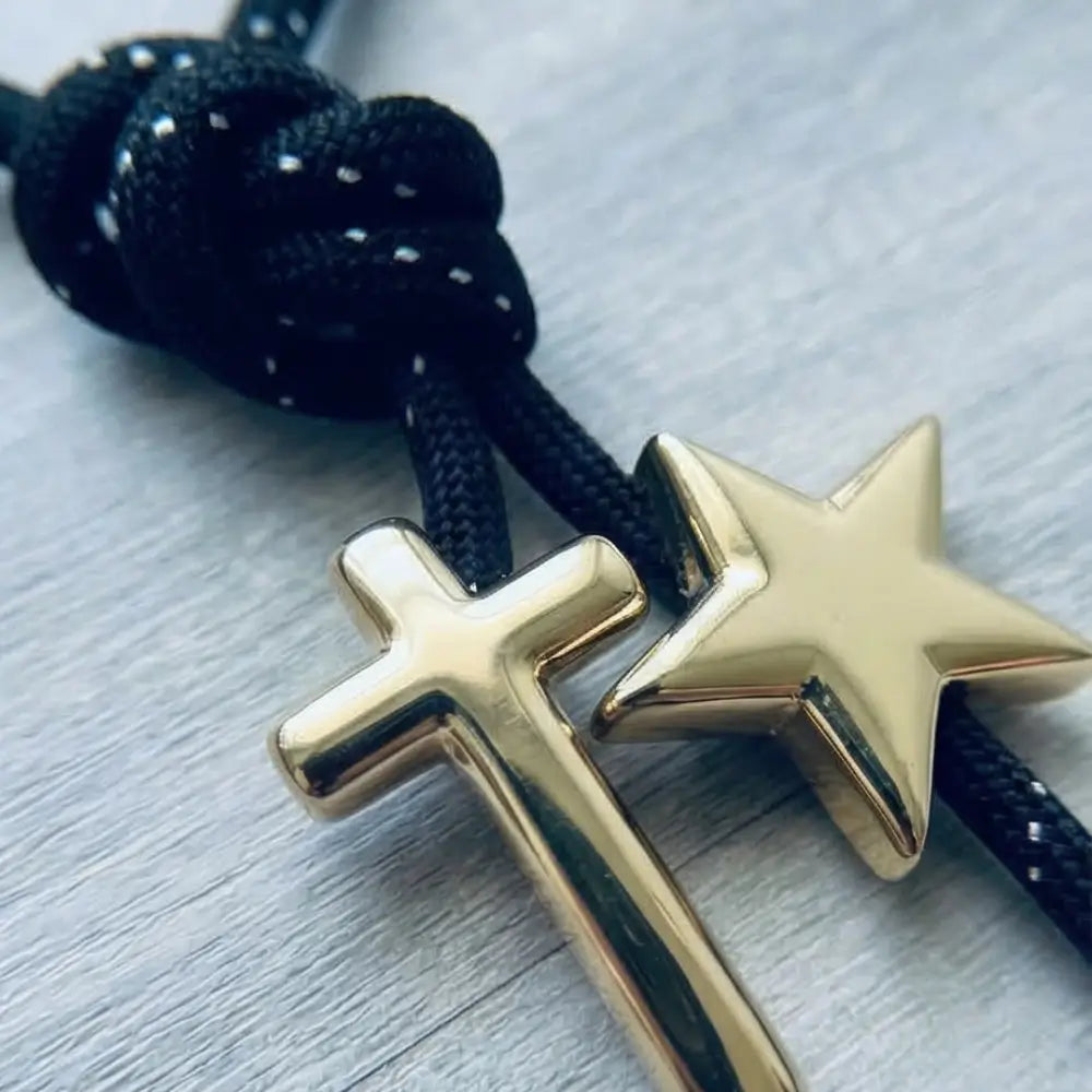 Close up black paracord necklace with gold cross and star charms luxury minimalist jewelry detail