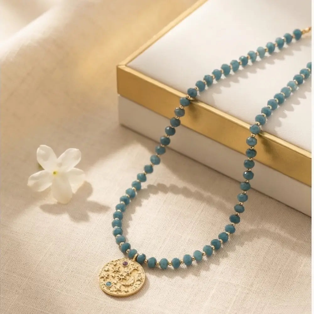 Blue Amethyst Beaded Necklace with Gold Celestial Medallion styled on jewelry box, elegant celestial pendant necklace for women.