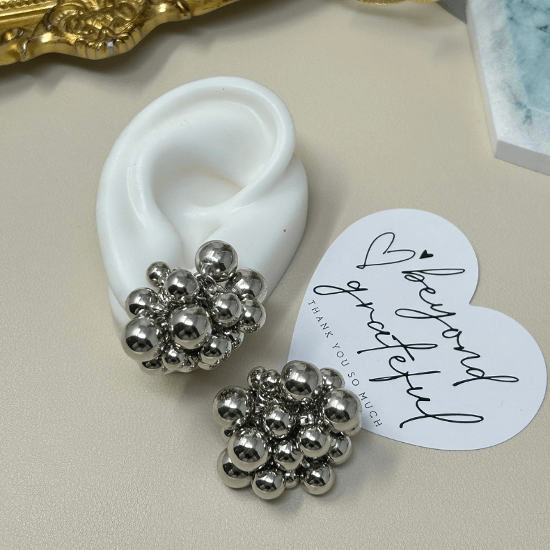 Elegant gold cluster earrings composed of multiple polished gold spheres arranged in a unique and eye-catching design. Perfect for adding a touch of sophistication and glamour to any outfit, suitable for business women aged 35 to 60."