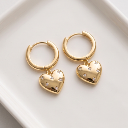 Close-up of a polished gold-tone heart charm decorated with scattered clear sparkling accents