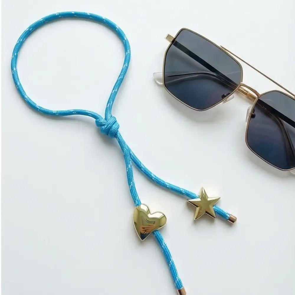 Blue cord with heart and star charms and sunglasses on a white background