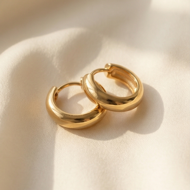 Pair of gold hoop earrings on a beige fabric background