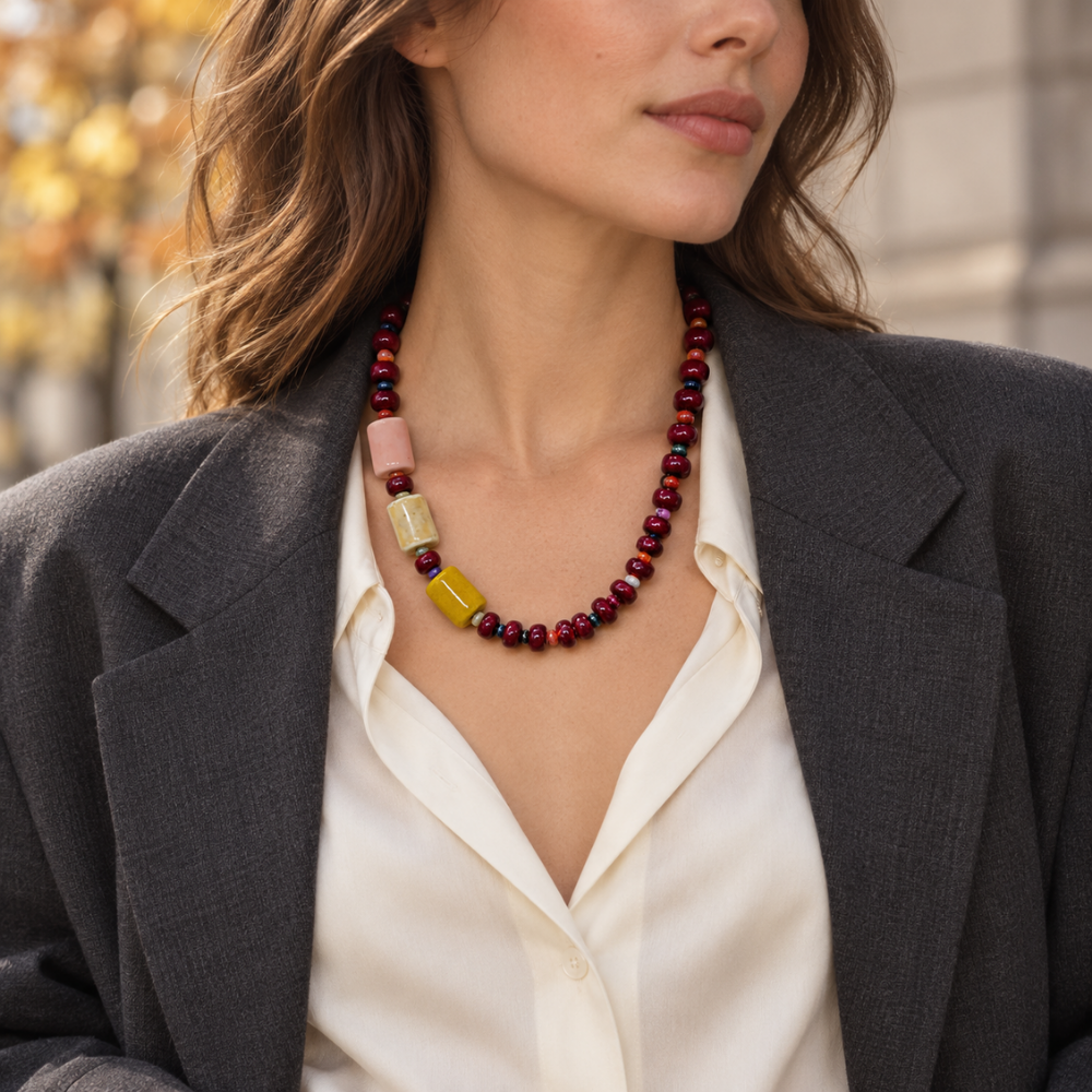 Woman wearing the asymmetric Bordeaux Colorblock Necklace with an ivory blouse and charcoal blazer.