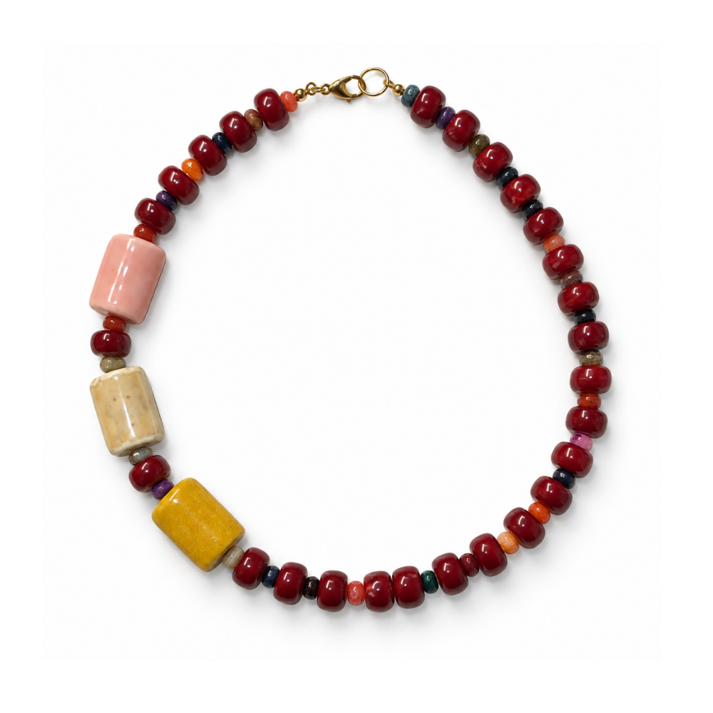 Bordeaux beaded necklace with three oversized blush, cream and ochre beads arranged asymmetrically on one side.
