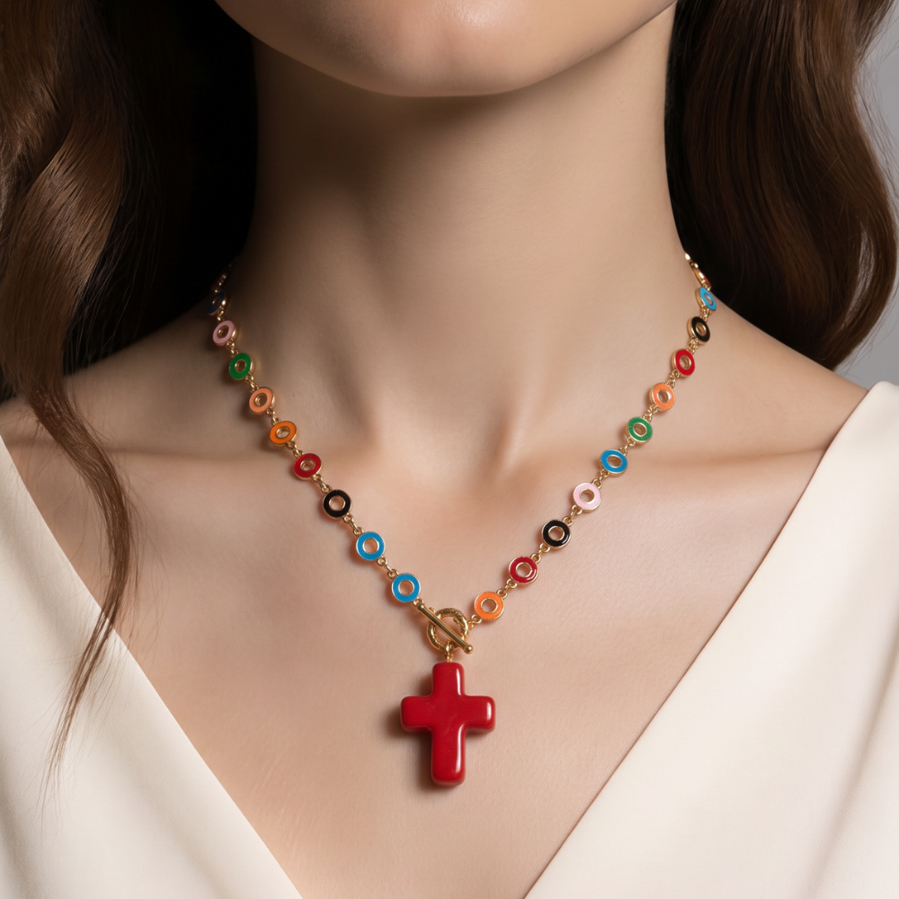 A close-up of a model wearing a colorful beaded necklace with a red cross pendant. The necklace features gold-toned links and small circular beads in multiple colors including orange, green, blue, pink, and black.