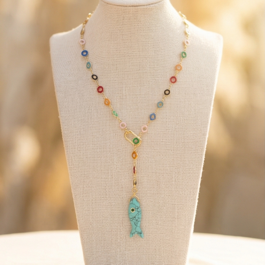 Necklace with colorful beads and a turquoise fish pendant on a mannequin bust.