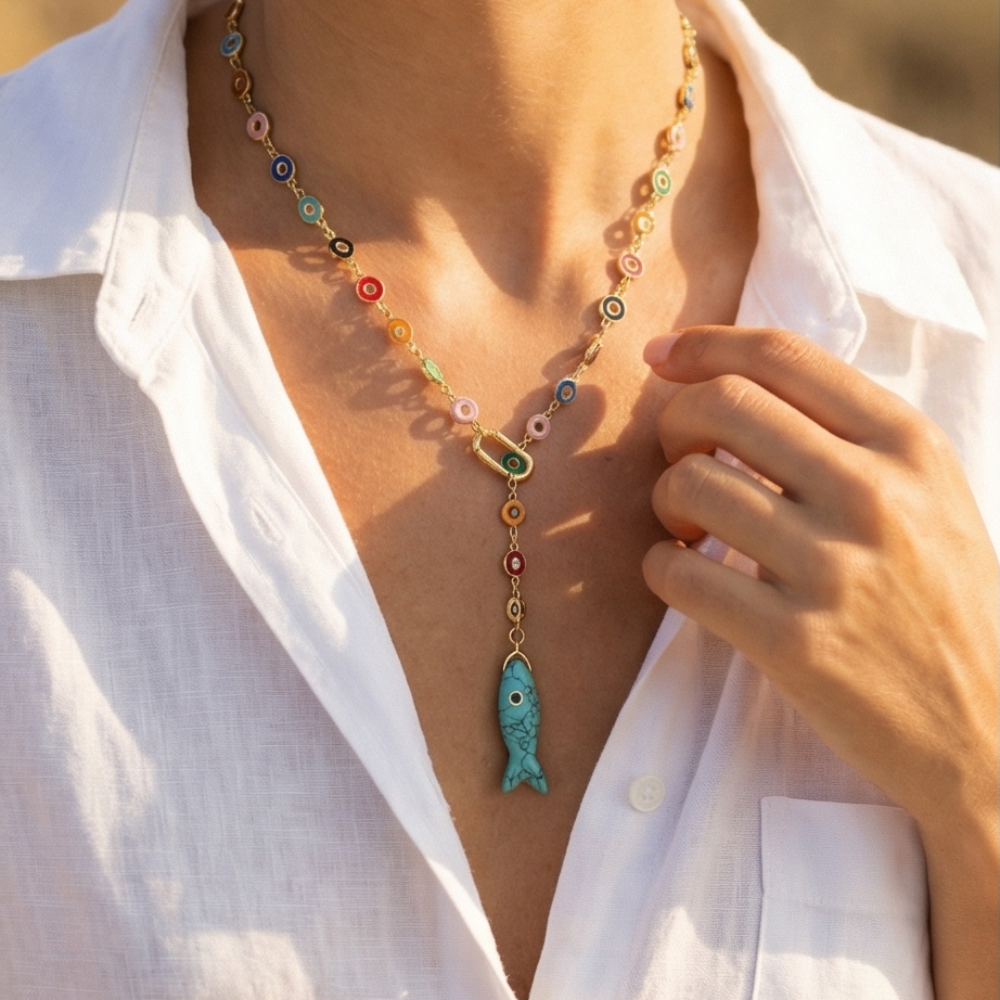 Colorful beaded necklace with a fish pendant worn by a person in a white shirt.