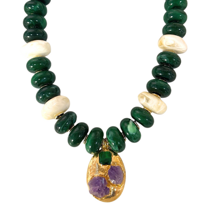 Close-up of woman wearing Emerald Relic Necklace with deep green and marbled off-white acrylic beads and gold-tone green and purple pendant