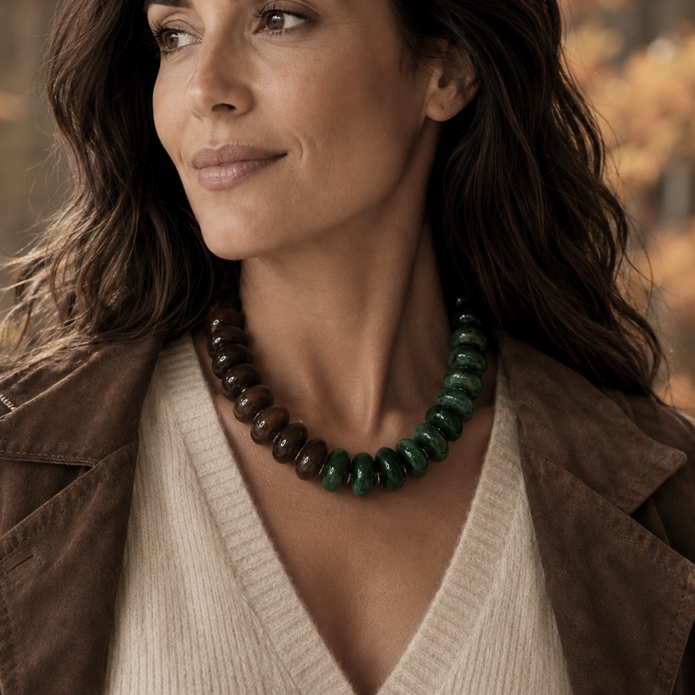 Close-up of woman wearing Forest Ember necklace with deep green and warm brown acrylic beads and gold-tone accents