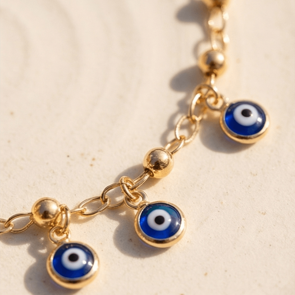 Gold bracelet with blue evil eye charms on a beige background