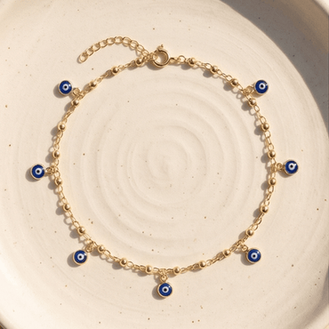 Gold evil eye anklet bracelet with blue charm details on delicate chain.