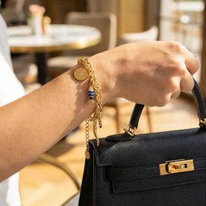 Woman wearing gold charm bracelet with love pendant and blue fish charm by Julie Saldivia Jewelry