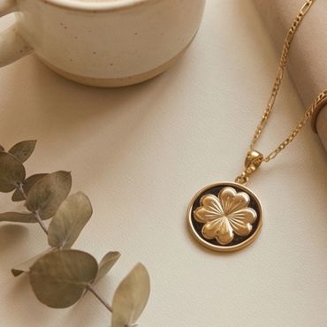 Gold clover pendant necklace styled with coffee cup and journal on neutral background