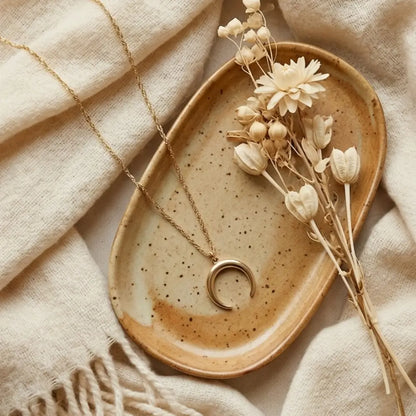 Gold crescent moon necklace on neutral background minimal celestial jewelry