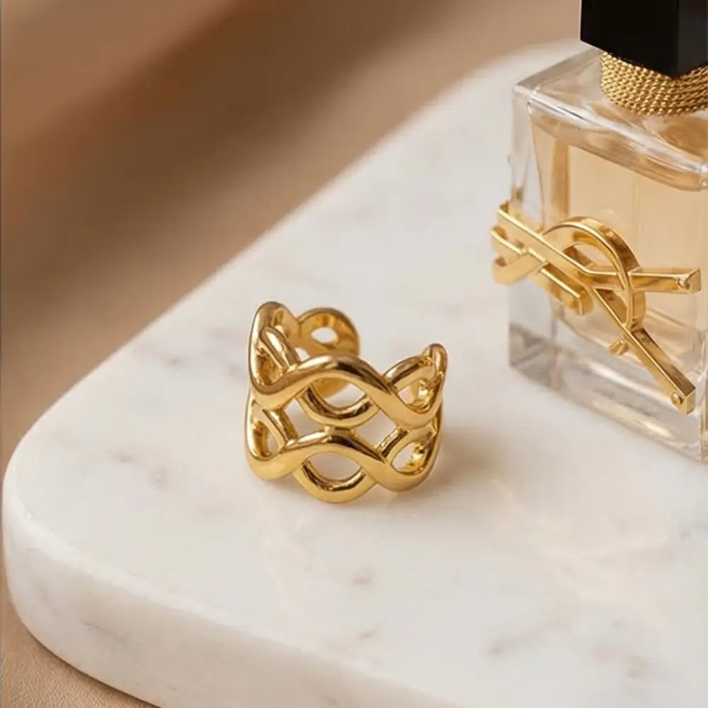 gold crossover ear cuff on marble surface luxury jewelry detail Julie Saldivia