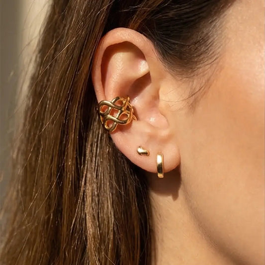 gold crossover ear cuff on marble surface luxury jewelry detail Julie Saldivia