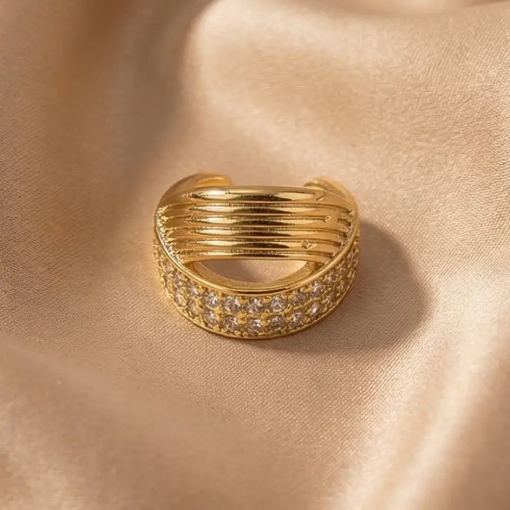 Gold ring with embedded stones on a beige fabric background